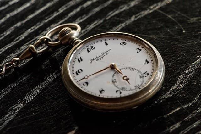 beautiful antique pocket watch lying on dark wood.