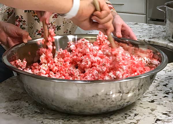genibliss stirring hot popcorn with red syrup to coat popcorn