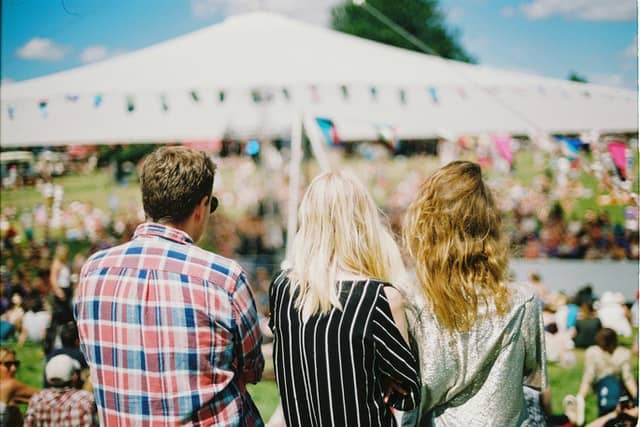 the back of three people looking at a blurred scene under a tent like a large family reunion