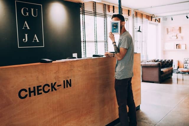 man standing at a counter desk with the word check-in as if checking if for family reunion